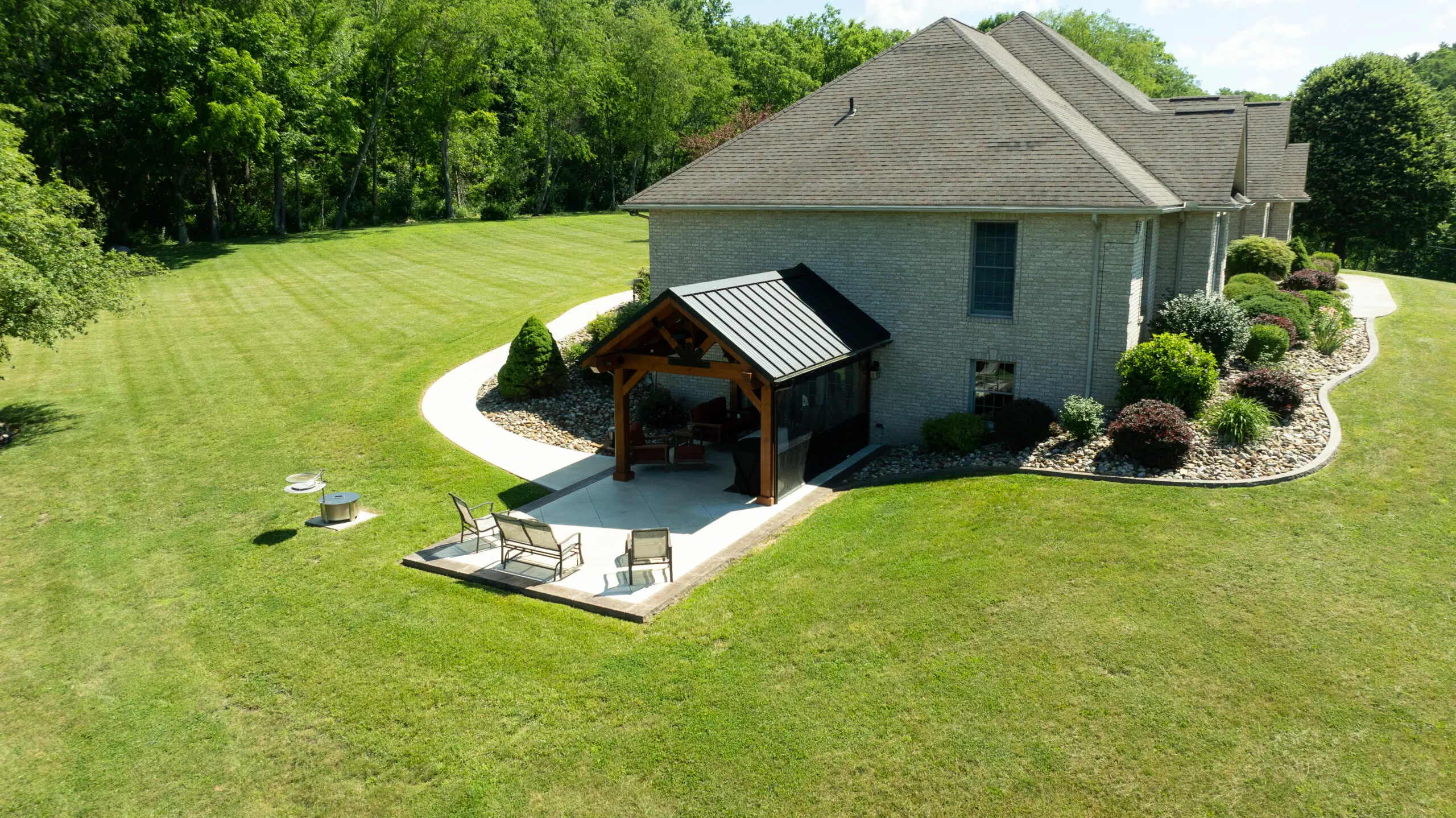 Aerial view of a Creekside pavilion and patio beside a brick home in Fresno, Ohio