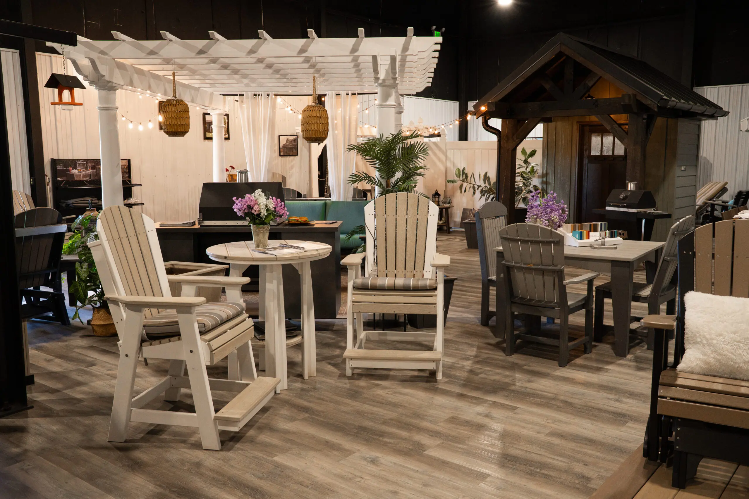 Poly outdoor furniture arranged under a white pergola inside the Creekside showroom
